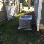 A residential air conditioner outside in the yard.