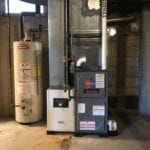 A gas furnace and water heater in an unfinished basement.